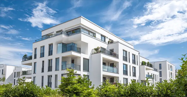 Moderne weiße Wohnanlage mit Balkonen und blauen Himmel