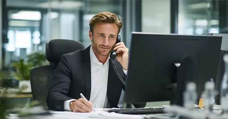 Mann im Anzug telefoniert am Schreibtisch
