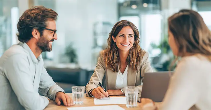 Drei Personen bei der Besprechung eines Immobilienkaufvertrags